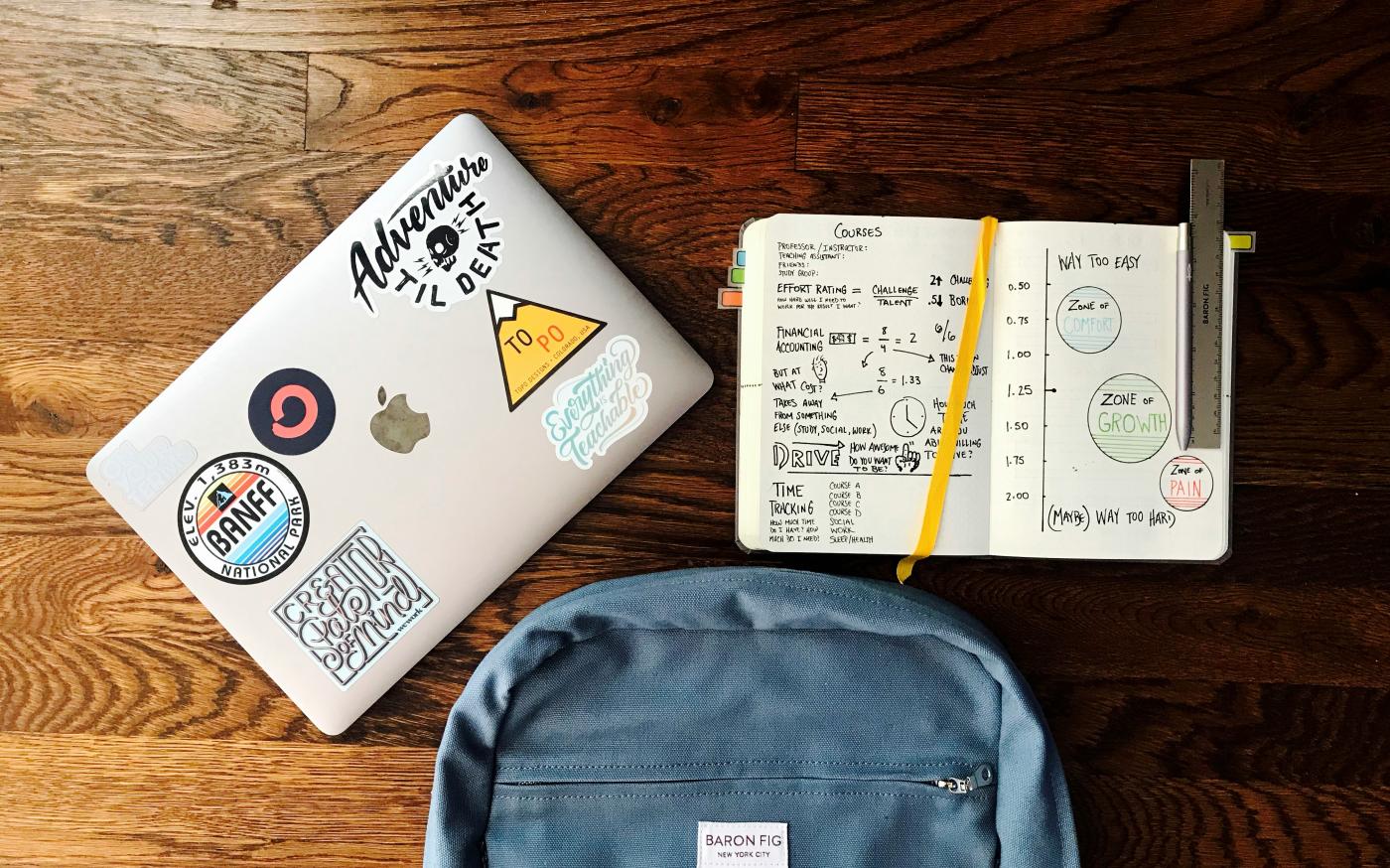 flat lay photography of blue backpack beside book and silver MacBook by Matt Ragland courtesy of Unsplash.