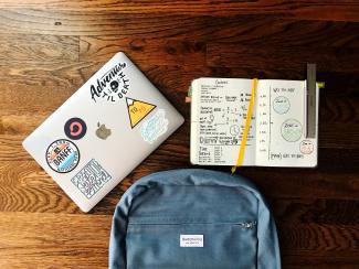 flat lay photography of blue backpack beside book and silver MacBook by Matt Ragland courtesy of Unsplash.