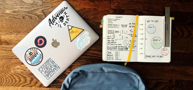 flat lay photography of blue backpack beside book and silver MacBook by Matt Ragland courtesy of Unsplash.